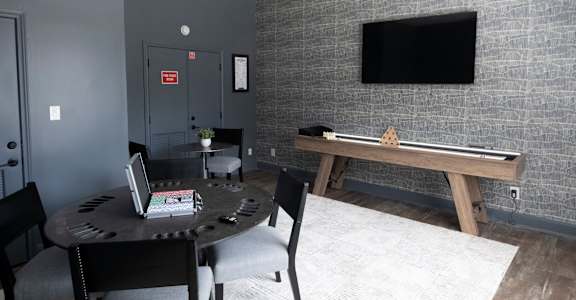 A room with a table, chairs, and a TV mounted on the wall.