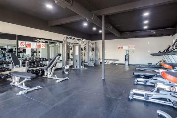 a gym with weights and cardio equipment on the floor and a wall of mirrors