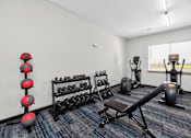 Thumbnail 8 of 11 - A gym with a variety of equipment including dumbbells, weight plates, and a bench press.