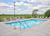 Thumbnail 6 of 11 - A pool with a metal ladder and white chairs.