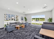 Thumbnail 2 of 11 - A spacious waiting room with grey and black furniture and a large window showing the outside.