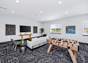 Thumbnail 3 of 11 - A foosball table is in the middle of a room with a couch, chair, and table.