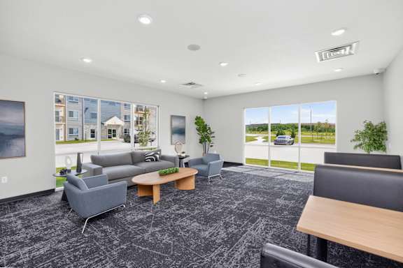A spacious waiting room with grey and black furniture and a large window showing the outside.