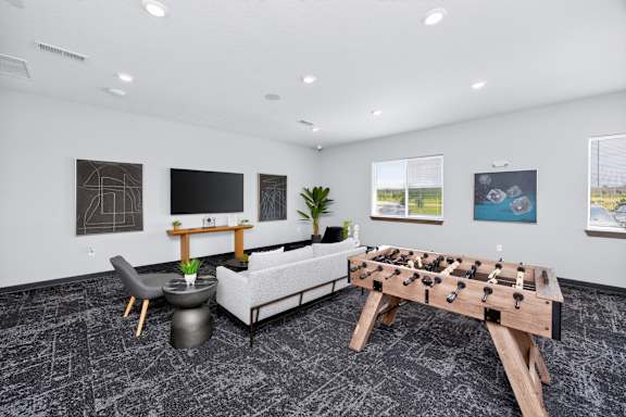 A foosball table is in the middle of a room with a couch, chair, and table.
