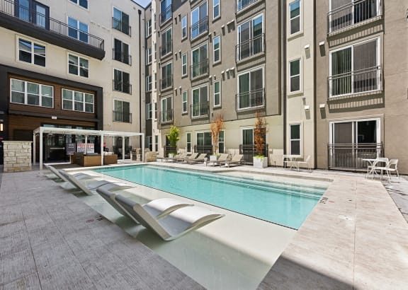 an outdoor area with lawn chairs and a pergola in an apartment building