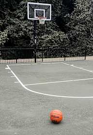 A basketball is on the ground near a basketball hoop.