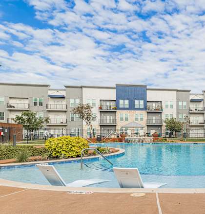 a swimming pool at an apartment building with chairs around it