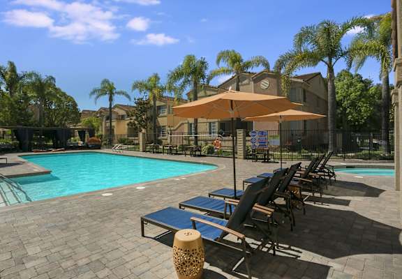 a swimming pool with chaise lounge chairs and umbrellas at Arroyo Villa Apartments, Thousand Oaks, CA