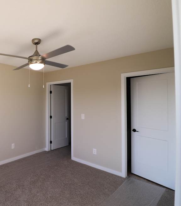 A room with a ceiling fan and two doors.