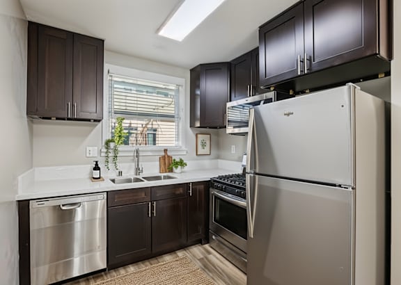 a kitchen with black cabinets and stainless steel appliances and a white counter top