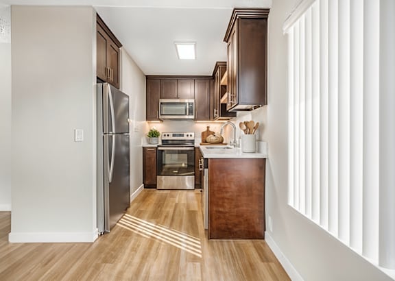 a kitchen with black cabinets and stainless steel appliances and a white counter top