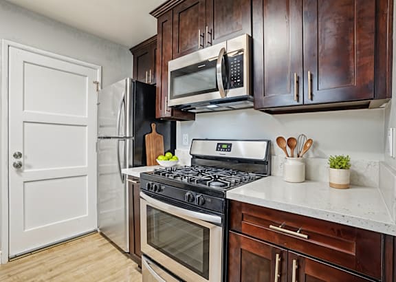 a kitchen with black cabinets and stainless steel appliances and a white counter top