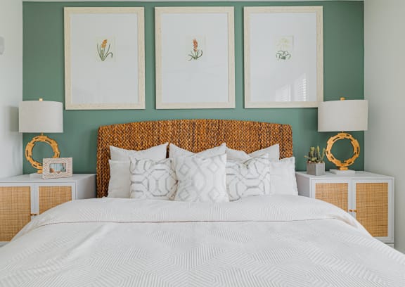 a bedroom with green walls and a white bedspread and rattan headboard