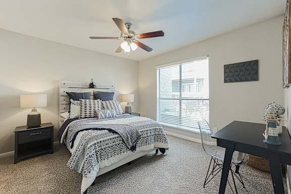 A bedroom with a bed, nightstand, and a table with a vase on it. at Cashel Springs, Texas, 77069