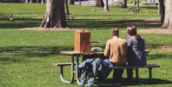 a couple sitting at a picnic table in a park