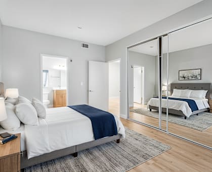 A bedroom with a large bed and a mirror on the wall.
