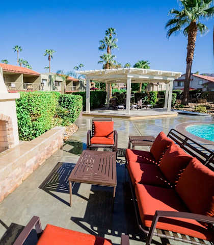 a patio with furniture and a fireplace next to a pool