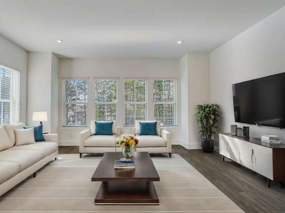 Henley Avondale Townhomes near Scottdale, GA photo of a living room with white couches and a coffee table, hardwood floors and large windows