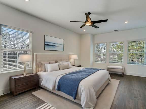 Henley Avondale Townhomes near Scottdale, GA photo of a master bedroom with a large bed and a ceiling fan and hardwood floors