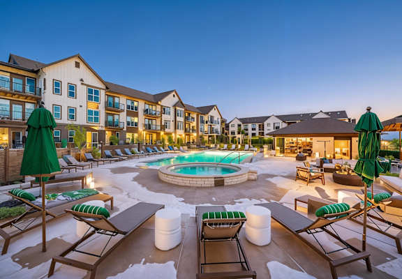 A large outdoor pool area with lounge chairs and umbrellas.