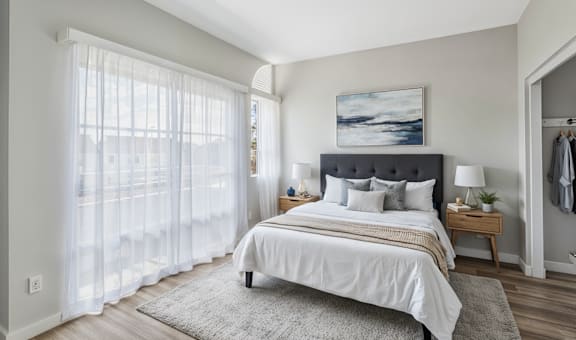 A bedroom with a large bed and a painting on the wall.