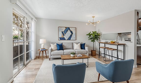 A living room with a couch, two chairs, and a dining table.