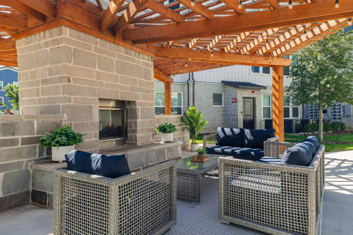 a covered patio with furniture and a stone fireplace