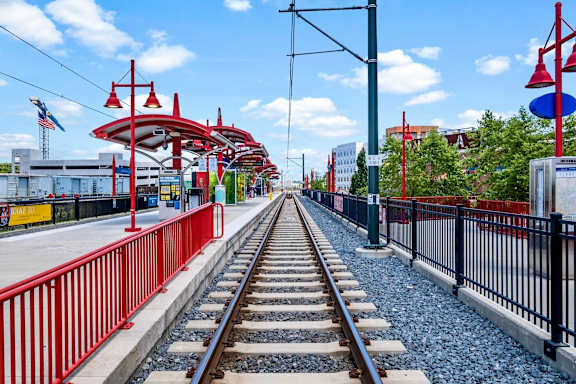 a train station with train tracks and a red and black fence at The Collection Charlotte in Charlotte, NC, 28205