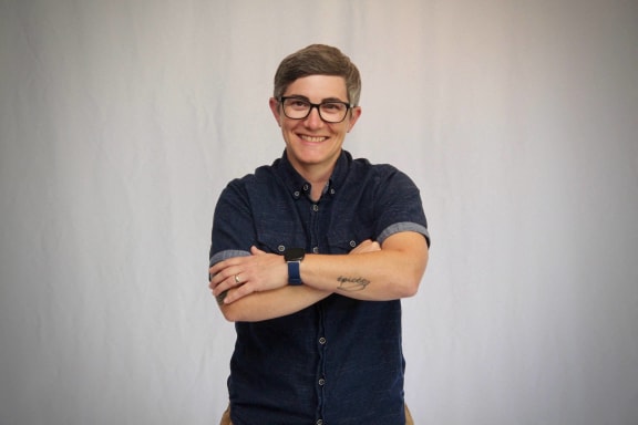 a young man with glasses smiling in front of a microwave