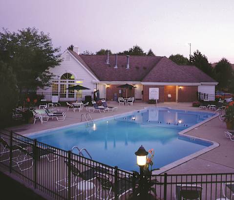 A pool and patio area of a house with a lamp post in the foreground.