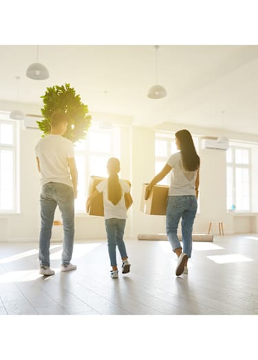 A family of three is walking through a bright, spacious room.