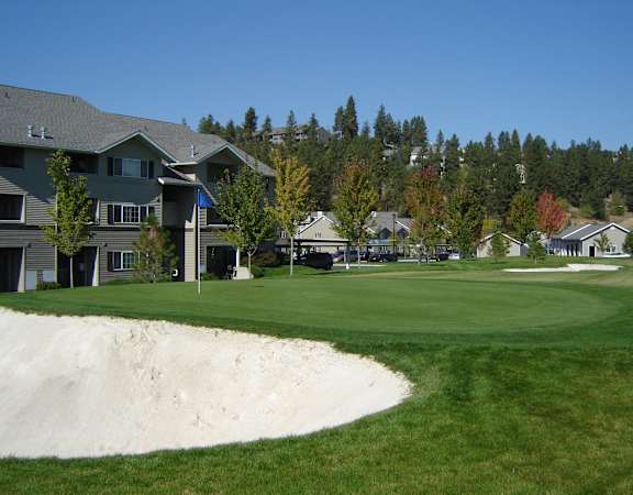 A golf course with a sand trap in the foreground and houses in the background.