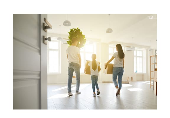 A family of three is walking through a bright, spacious room.