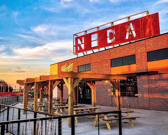 A red sign with the letters "NEDA" on top of a building with picnic tables in front.