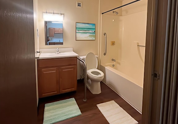 A bathroom with a toilet, sink, and mirror.
