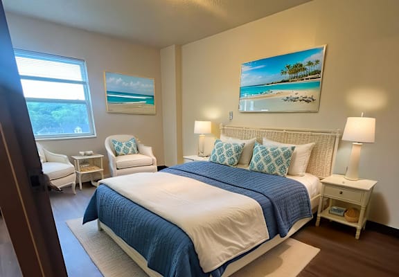 A bedroom with a bed, two chairs, and a painting on the wall.