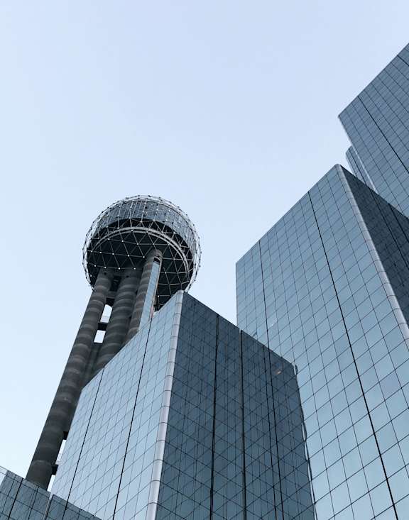 A tall glass building with a spherical observation deck on top.
