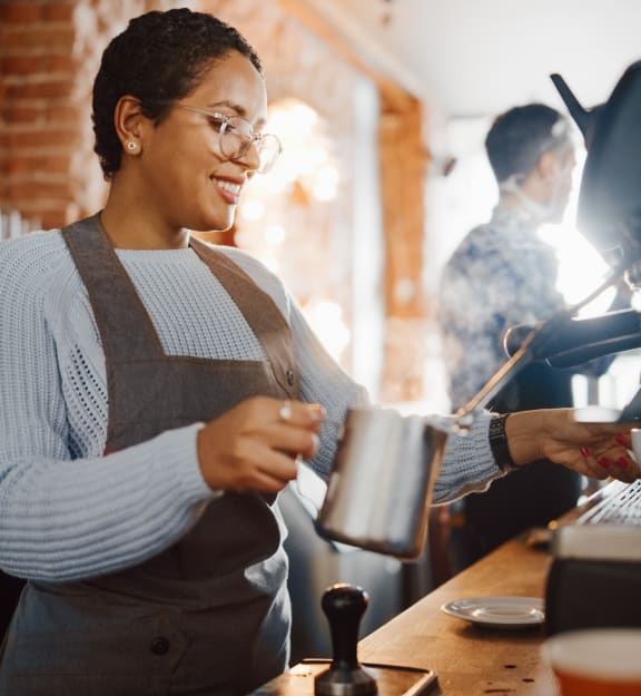 a barista making a cup of coffee in a coffee shop at Renaissance Park Apartments, California, 95618