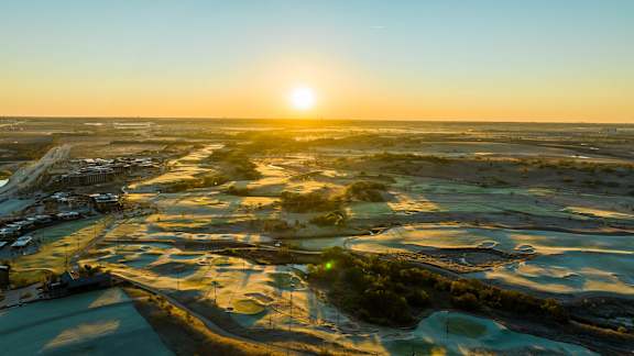 The sun is setting over a landscape with a mix of water and land.