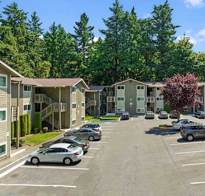 A parking lot with cars and apartment buildings in the background.