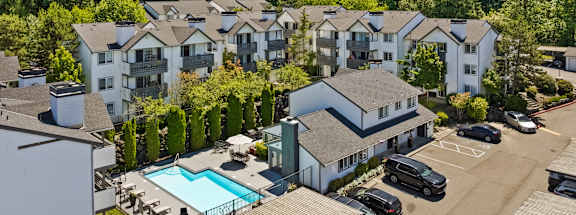 an aerial view of a building with a swimming pool and other buildings