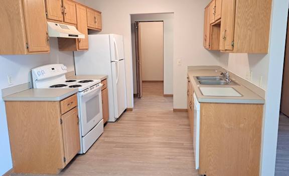 a kitchen with white appliances and wooden cabinets