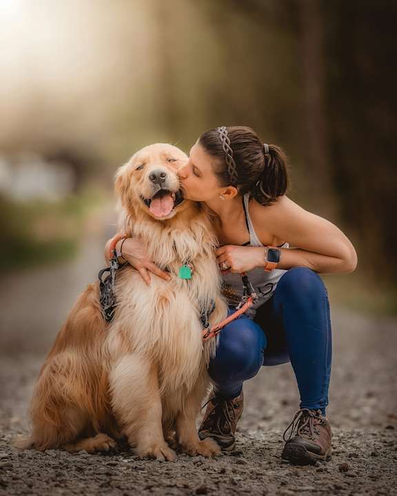 A woman is hugging a golden retriever in an outdoor setting.