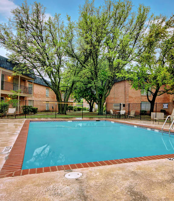 A swimming pool surrounded by a fence and trees.