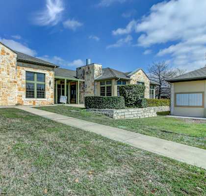 A house with a stone wall and a green fence.