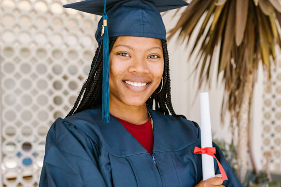A person in a graduation gown holding a diploma.