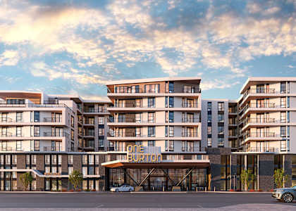 A modern multi-story residential building with a parking lot in front.