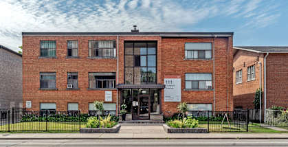 A red brick building with a black fence in front.at 111 Cosburn, East York Ontario