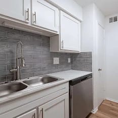 A kitchen with white cabinets and a black fridge.
