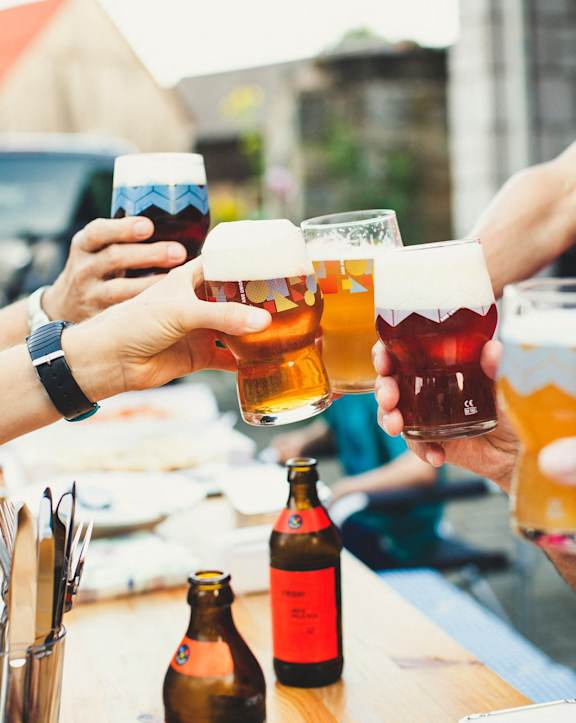 a group of people sitting at a table drinking beer and eating food